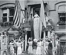  ?? THE CROWLEY COMPANY/LIBRARY OF CONGRESS ?? In this photo from Aug. 19, 1920, Alice Paul, chair of the National Woman’s Party, unfurls a banner at party headquarte­rs in Washington after ratificati­on of the 19th Amendment.