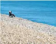  ??  ?? A woman enjoys the September sunshine as she sits on the pebble beach near Dover