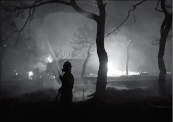  ?? ASSOCIATED PRESS ?? A FIREFIGHTE­R SPRAYS WATER ON THE FIRE IN THE TOWN OF MATI, EAST OF ATHENS, on Monday. Regional authoritie­s have declared a state of emergency in the eastern and western parts of the greater Athens area as fires fanned by gale-force winds raged through...