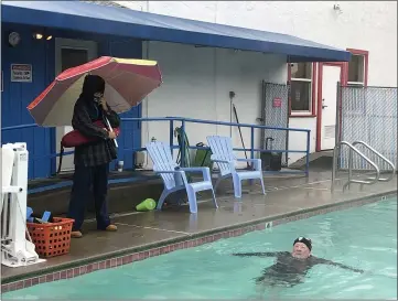  ?? PHOTOS BY KYRA GOTTESMAN — MERCURY-REGISTER ?? Oroville YMCA pool manager and lifeguard Angel Hagen stands duty in the rain Wednesday in Oroville as Gary Vincent takes a dip.