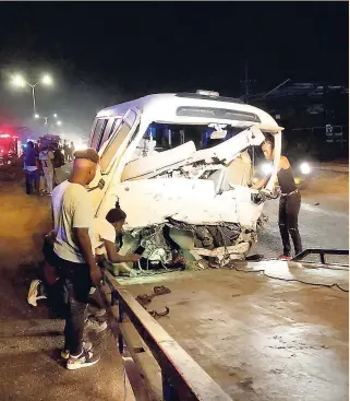  ??  ?? These men were seen trying to get the Coaster bus on to the wrecker, following the two-vehicle collision yesterday on Spanish Town Road, Kingston.