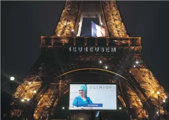  ?? JACK CHAN / XINHUA ?? A portrait of a nurse who was mobilized during the COVID-19 pandemic is displayed on a giant screen in front of the Eiffel Tower in Paris, on Sunday.