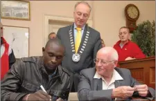  ??  ?? David Rudisha and Br Colm O’Connell signing the visitors book at the former Mallow Town Hall, were there was a civic reception held in their honour during their 2013 viist to the town.