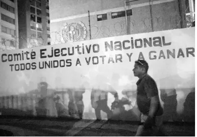  ?? AP ?? Opposition militants and journalist­s gather outside the Democratic Action political party headquarte­rs, where a sign reads in Spanish, “National Executive Committee.”