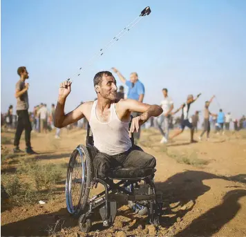  ?? REUTERS ?? A disabled Palestinia­n hurls stones at Israeli troops during a protest in Gaza on Saturday.