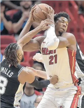  ?? MICHAEL LAUGHLIN/SUN SENTINEL ?? The Heat’s Hassan Whiteside moves to the basket while guarded by Spurs guard Patty Mills and Jakob Poeltl, back, during Wednesday’s game. Whiteside finished with 29 points, 20 rebounds and nine blocks.