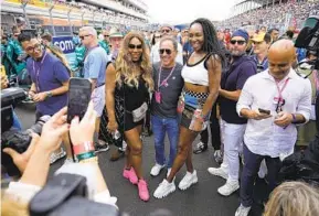  ?? REBECCA BLACKWELL AP ?? Serena Williams (left) and sister Venus Williams (right) pose for a photo with a fan on the starting grid just before the start of the Formula One Miami Grand Prix.