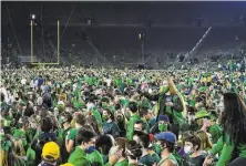  ?? Pool / Getty Images ?? Fans storm the field after No. 4 Notre Dame defeated No. 1 Clemson 4740 in double overtime in South Bend, Ind.