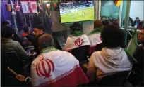  ?? HUSSEIN MALLA — THE ASSOCIATED PRESS ?? Lebanese soccer fans of Iran's team cover their backs with Iranian flags, as they sit at a coffee shop smoking water pipes watching the World Cup group B match between Iran and the U.S. on Tuesday.