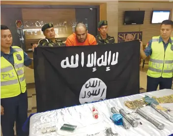  ?? FOTO COURTESY OF PNP-PIO ?? TERROR THREAT. Police say they have foiled a terror threat with the arrest of suspected terrorist Fehmi Lassoued (in orange top). The suspect was presented before the media together with the items allegedly seized from him and his Filipina partner.