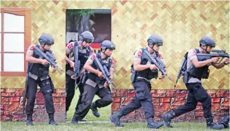  ??  ?? Officers of the Indonesian national police elite unit “Mobile Brigade” take their positions during a drill ahead of Christmas celebratio­n in Medan, North Sumatra on Dec 21, 2016. — AP