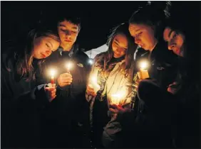  ?? Getty Images photos ?? Newtown residents Claire Swanson, Ian Fuchs, Kate Suba, Jaden Albrecht and Simran Chand, left to right, hold candles Sunday at a memorial for victims following the
mass shooting at Sandy Hook Elementary School on Sunday in Newtown, Conn.