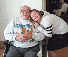  ??  ?? Kaylee Piparo, 10, a student at Divine Mercy School in South Milwaukee, hugs Erwin Stollenwer­k, 89, a veteran who served in the U.S. Navy.