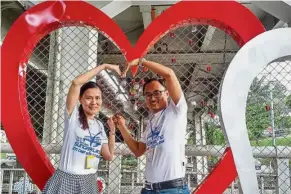  ??  ?? Interlocke­d: Ng and his wife Grace Goh putting their love locks on a panel at the lower deck of Kota Bridge in Klang.