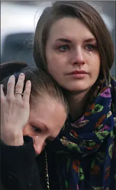  ??  ?? Tears: Women watch the coffins arrive in St Petersburg