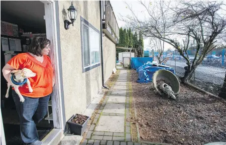  ??  ?? Stacey Rumsby, with her dog Oscar, looks out from her home toward the Galloping Goose trail. Expropriat­ion should be an option, Rumsby says. “No one will buy our house now.”