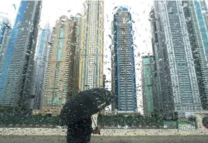  ?? Pawan Singh / The National ?? A pedestrian near Dubai Marina raises the umbrella for yet another day yesterday. The brolly will be getting even more of a workout over the next week, the weather bureau says, and you shouldn’t put the coat in mothballs just yet.
