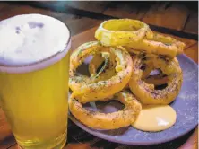  ??  ?? Beer-battered onion rings with a brew, above, at Starline Social Club in Oakland. Left: Rack of lamb with oyster mushrooms, grilled Jimmy Nardello peppers, kale salsa verde.