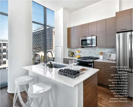  ??  ?? caption tk Let there be light: One of the sun-filled, city-facing model units at NEXT Apartments in River North, featuring quartz countertop­s and stainless steel appliances, glass tile backspash, oak-faced flat paneled cabinets, and plank flooring.