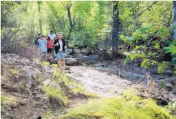  ?? ANGIE WANG/ASSOCIATED PRESS ?? Members of the family of Hector Garnica walk along the riverbank as they and first responders search for the missing man. Other members of the family and friends were killed in a flash flood Saturday.