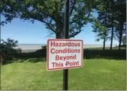  ?? ANDREW CASS - THE NEWS-HERALD ?? Signs in Madison Township’s Bill Stanton Community Park warn visitors of erosion issues.