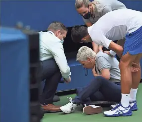  ?? DANIELLE PARHIZKARA­N/USA TODAY SPORTS ?? Novak Djokovic and a tournament official tend to a linesperso­n who was struck with a ball by Djokovic on Sunday.