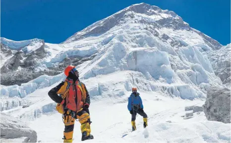  ?? FOTO: TSHIRING JANGBU SHERP/DPA ?? Khim Lal Gautam (li.) schaut auf dem Weg zum Lager 1 auf dem Mount Everest nach oben. Die meisten Abenteurer versuchen die Todeszone oben auf dem höchsten Berg der Erde schnell zu verlassen. Aber Khim Lal Gautam musste länger bleiben. Er sammelte wichtige Daten, damit wir genauer wissen, wie hoch der Mount Everest wirklich ist.