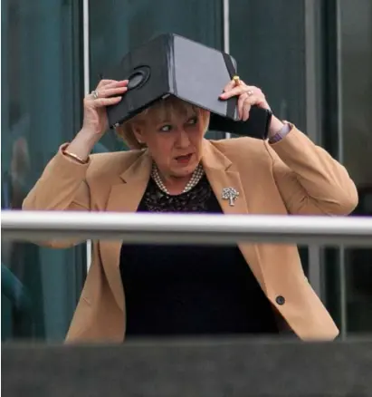  ??  ?? RUNNING FOR COVER: Fine Gael’s Heather Humphreys uses her iPad to protect her hair as she arrived at the Convention Centre where Micheal Martin was elected Taoiseach