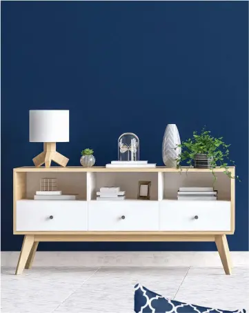  ??  ?? Painting an accent wall in Classic Blue can help make furniture stand out from the background.The color pairs well with a variety of wood tones.