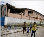  ?? DIEU NALIO CHERY / ASSOCIATED PRESS ?? Residents pass a school Sunday damaged by a magnitude 5.9 quake the night before in Gros-Morne, Haiti. Emergency teams worked to provide relief after the quake killed at least 12 and injured 188.