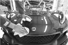  ??  ?? An employee polishes a Lotus Exige sports coupe automobile as it moves down the inspection line at Group Lotus in Hethel.