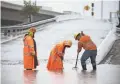  ?? MARK HENLE/THE REPUBLIC ?? Mike Culp (from left), Alex Munoz and Alan Garcia clear a drain on Interstate 10.