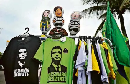  ?? Pilar Olivares/Reuters ?? Camisas de Bolsonaro e bonecos à venda nesta quinta em frente ao condomínio onde mora Bolsonaro, no Rio