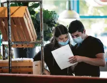  ?? Annie Mulligan / Contributo­r ?? Camila Bizcaino and David Cisneros look over the menu at the Heights location of Local Foods, which served walk-in diners.