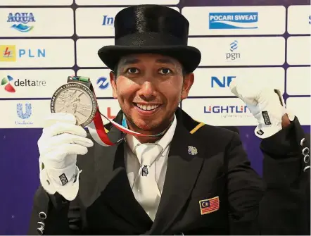  ??  ?? Costly affair: Malaysia’s equestrian rider Qabil Ambak happily posing with the dressage silver medal he won at the Jakarta Internatio­nal Equestrian Park yesterday. He spent almost RM1 million to prepare for the Games.