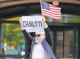  ?? Chip Somodevill­a Getty Images ?? A DEMONSTRAT­OR shares the news upon leaving court Tuesday in Alexandria, Va., where former Trump campaign chairman Paul Manafort was convicted.