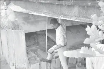  ?? (Ministry of the Presidency photo) ?? An Engineer from the Ministry of Public Infrastruc­ture examining the Bridge at Coomacka which they have said is on the verge of collapsing due to erosion..