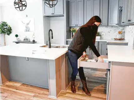  ?? Elizabeth Conley / Staff photograph­er ?? Realtor Katie Day grabs flyers out of a drawer in a model home in a new developmen­t she is marketing in Houston.