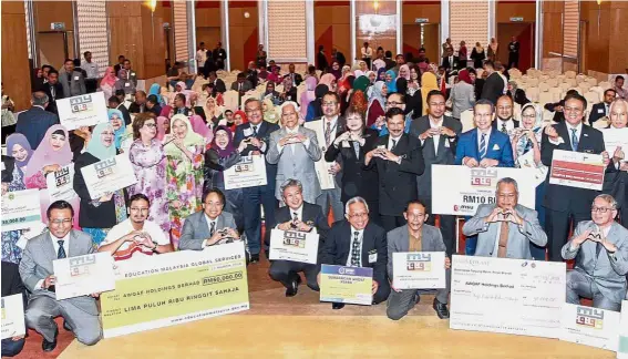  ??  ?? (Centre, standing) Idris and his deputy Datuk Dr Mary Yap posing with the mock cheques for MyWaqf in Putrajaya.