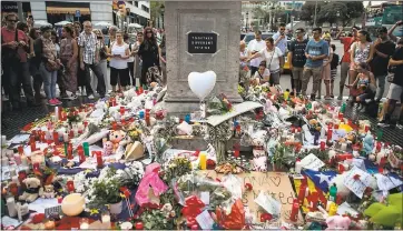  ?? CARL COURT — GETTY IMAGES ?? People gather around tributes laid on Las Ramblas on Friday near the scene of Thursday’s terrorist attack. Police say a terror cell’s plan to carry out an even deadlier attack was foiled when a house exploded in the Catalan town of Alcanar.