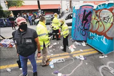  ?? Elaine Thompson Associated Press ?? POLICE INVESTIGAT­ORS collect evidence Monday after a teen was fatally shot in the “Capitol Hill Occupied Protest” area of Seattle. Nearby businesses and property owners have filed a lawsuit against the city.