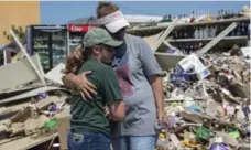  ?? CHRISTOPHE­R LEE/THE NEW YORK TIMES ?? Kelli Robinson is embraced by her mother, Lynette Robinson, amid the wreckage caused by hurricane Harvey in Port Aransas, Texas.