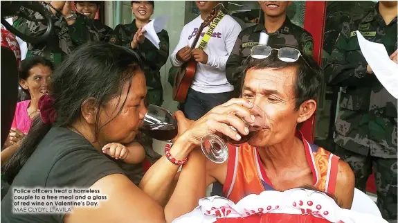  ?? MAE CLYDYL L. AVILA ?? Police officers treat a homeless couple to a free meal and a glass of red wine on Valentine’s Day.