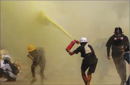  ?? (File Photo/ap) ?? An anti-coup protester uses a fire extinguish­er to provide cover for others March 17 as security forces approach their encampment in Yangon, Myanmar.