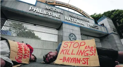  ?? Mark R Cristino / EPA ?? Demonstrat­ors play dead outside the Philippine national police headquarte­rs. They put cardboard signs with messages on them in the same style used by vigilantes killing drug addicts or sellers.