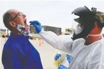  ?? DAVID H. LIPP/AIR NATIONAL GUARD ?? Maj. Preston Schaffner, of the 81st Civil Support Team, takes a swab sample from volunteer Scott Hennen in the parking lot of the Fargodome in Fargo, N.D., on April 25.