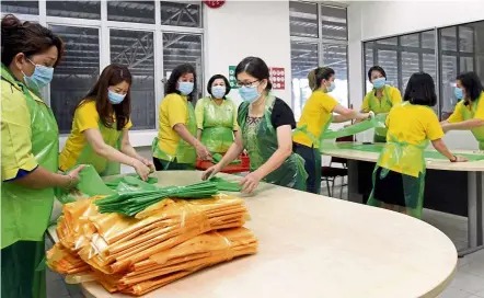  ??  ?? Group effort: Klang Wanita MCA members making plastic protective aprons that were donated to hospitals and health clinics in the Klang Valley.