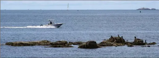  ?? ?? A boat glides past a rocky outcrop June 15 off Mingo Beach.