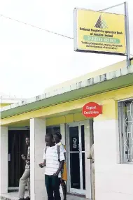  ??  ?? In this 2011 file photo, persons walk out of the National People’s Co-operative Bank’s Spaldings branch in Clarendon. The new regulator of the PC Bank plans to collect all of the outstandin­g loans on the lender’s books.