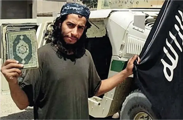  ??  ?? Propaganda: Abdelhamid Abaaoud, who is said to have mastermind­ed the Paris attacks, poses in Syria with a Koran and Islamic State flag for a magazine published by the group